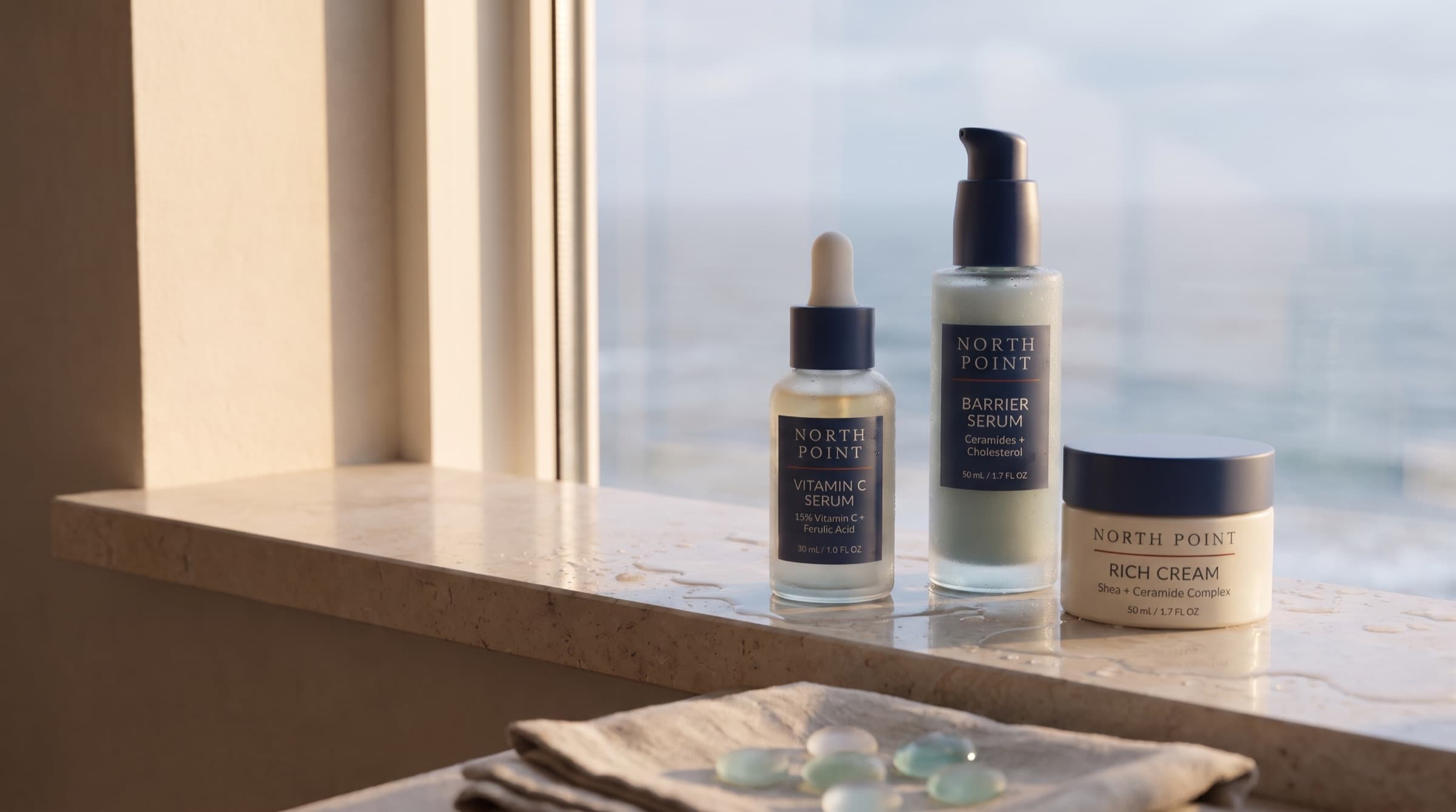 Vitamin C Serum, Barrier Serum and Rich Cream on a sunlit limestone windowsill above the sea